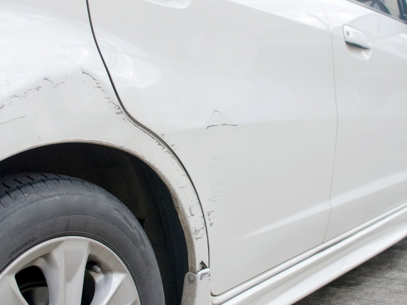 Local car dent repair for scratched rear wheel arch on white vehicle. 