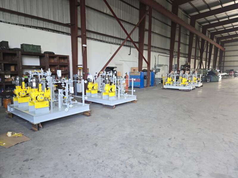 Custom fabricated chemical metering pump skid package with dual yellow diaphragm pumps, valve manifold, and painted structural steel base at WeldIT's Houston fabrication shop