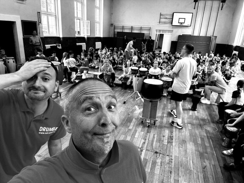 Zwei Musiker bei einem Trommelworkshop mit vielen Kindern