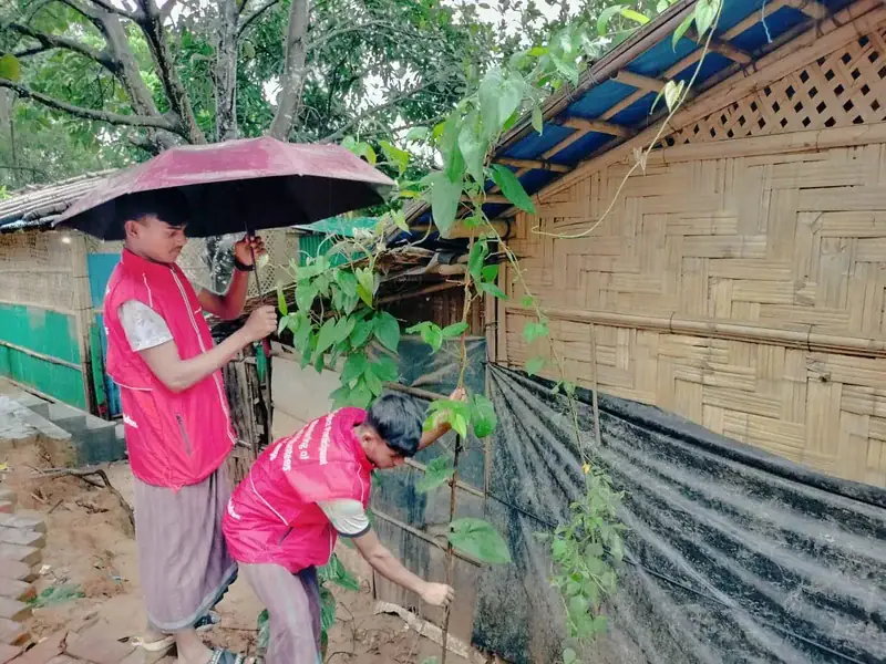 Nobi and Hakim reinforce fencing on a hillside in the camp, to prevent flooding.