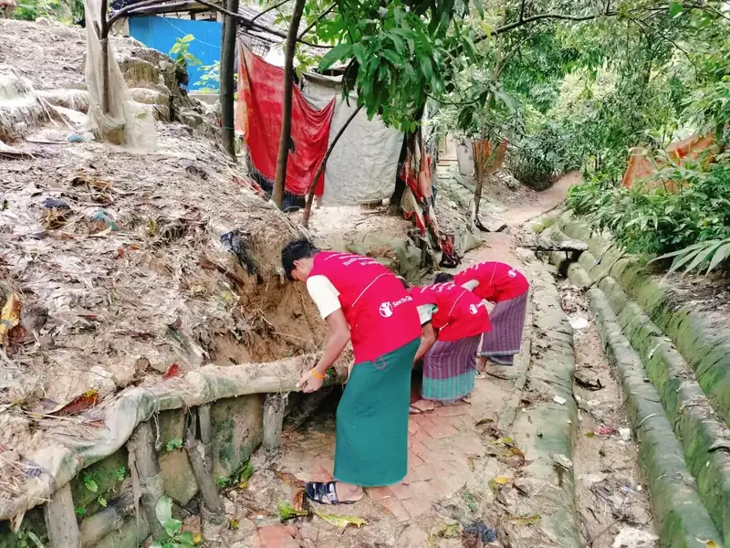 Musa, Nobi and Hakim work to repair a barrier that prevents walkways from being flooded during flash floods and rainstorms.