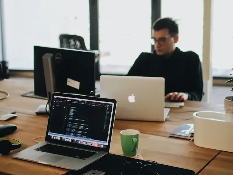 Arbeitsplatz mit Laptops und geöffnetem Programmcode zur technischen Umsetzung einer Website-Funktion.