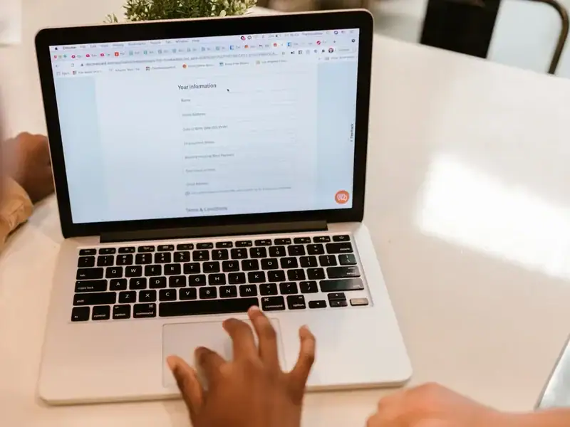 Person füllt auf einem Laptop ein Online-Formular mit persönlichen und vertragsbezogenen Angaben aus.