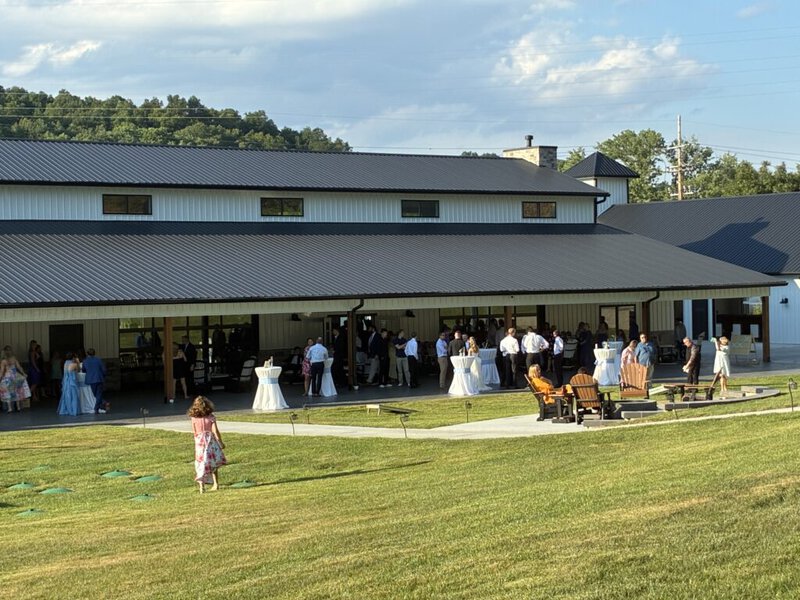 Exterior of the reception hall with wedding guests on the lawn at Romaine Valley Weddings & Events in Fenton, Missouri