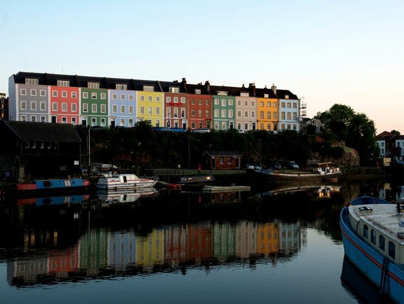 Bunte Häuser am Bristol Harbourside spiegeln sich im Wasser des Hafens.