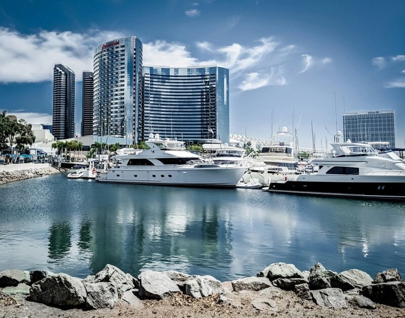 Luxusyachten im Hafen von San Diego mit modernen Hochhäusern und dem Marriott Hotel im Hintergrund.