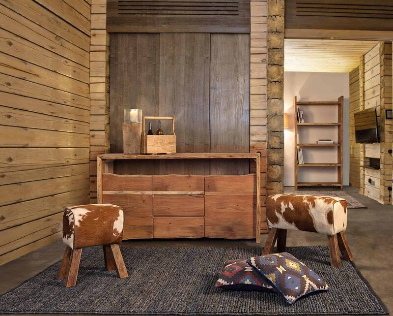 Appartamento con arredi in legno naturale, sedie rivestite in pelle e dettagli bohémien, ideale per ambientazioni rustiche e calde.