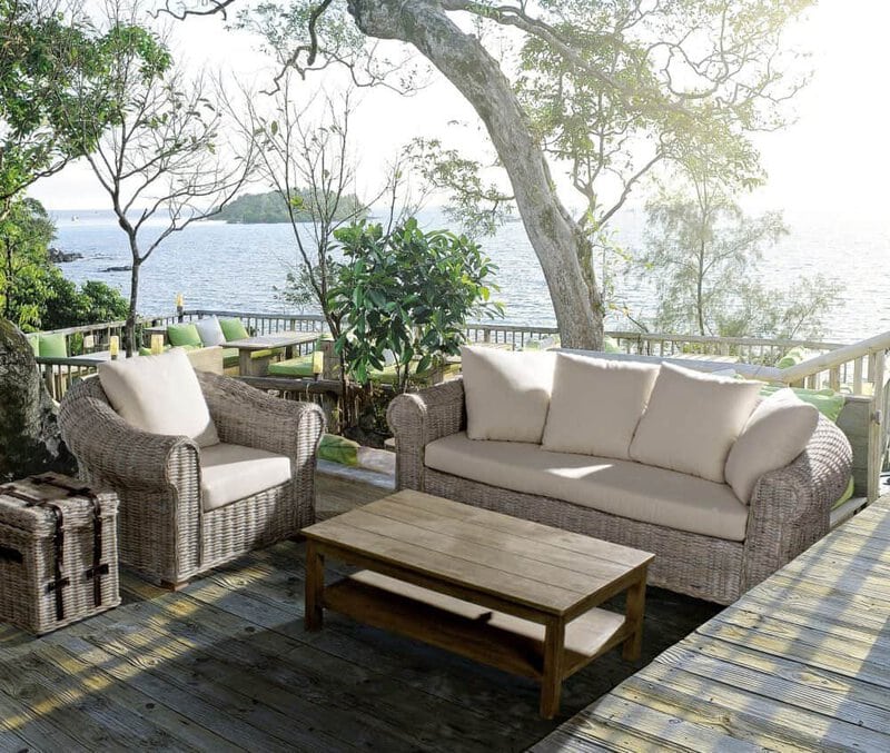 Area relax con mobili in rattan e vista mare, perfetta per il tempo libero in natura.