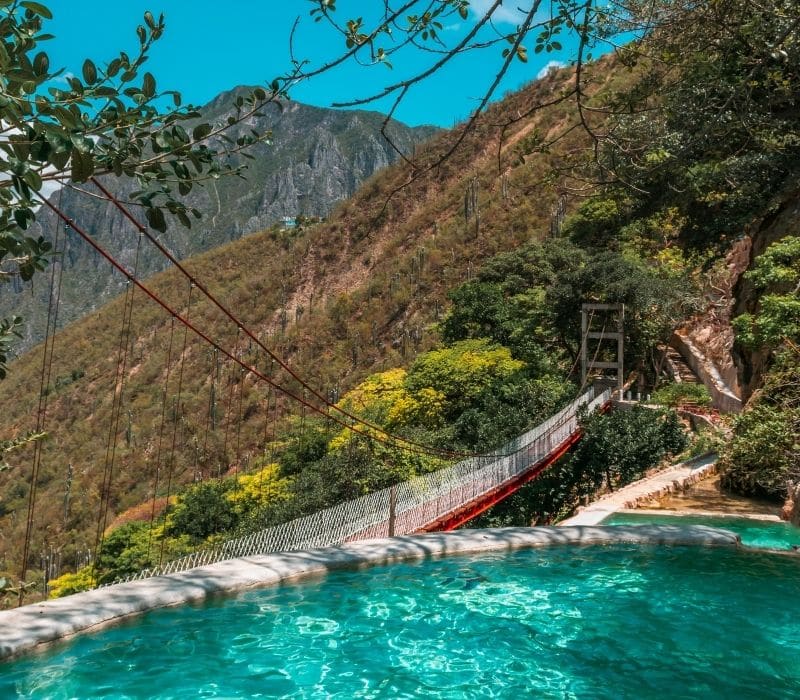 piscinas de agua azul con un puente al fondo - Visite Las Grutas Tolantongo