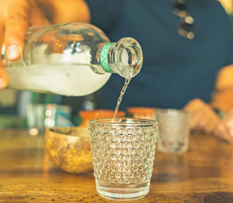 bartender pouring mezcal into a small cup