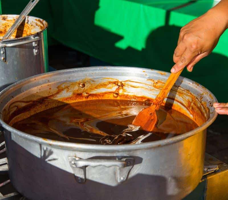stirring a large pot of mole in oaxaca mexico