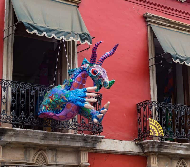 colorful alebrije statue in a window, which is a hybrid animal