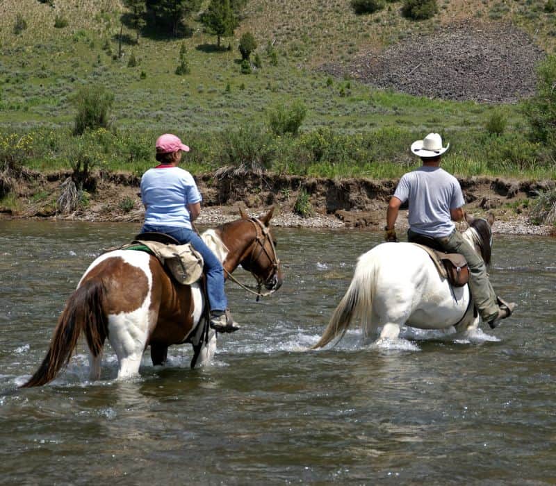 two people on a horseback ride through a river
