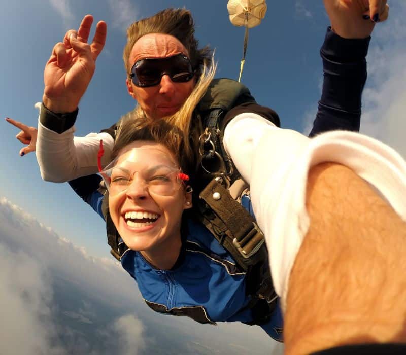 woman skydiving in tandem with man skydive instructor on her back