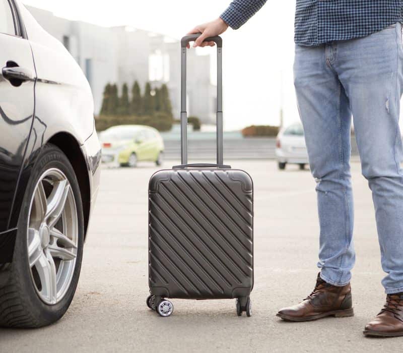man getting into car with his suit case