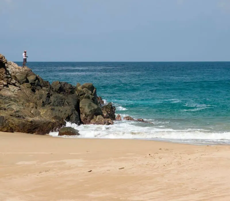 man fishing on the rocks - beach in Zipolite