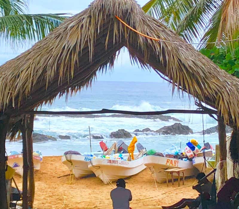 man on the beach in front of fishing boats in beach in San Agustinillo oaxaca mexico