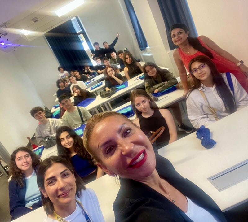 Lehrerin macht ein Selfie mit einer Gruppe von Schülern in einem Klassenzimmer.