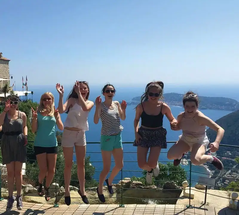 Eine Gruppe junger Sprachschüler genießt einen Ausflug an der Côte d’Azur mit atemberaubendem Meerblick.