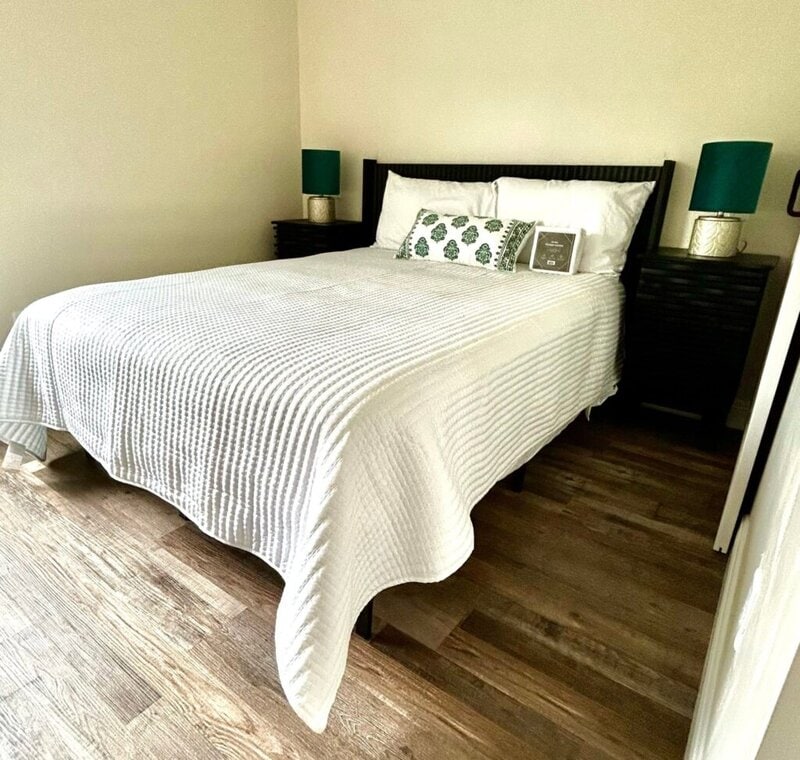 Bedroom with white quilted bedding in an on-site cottage at Romaine Valley Weddings & Events in Fenton, Missouri