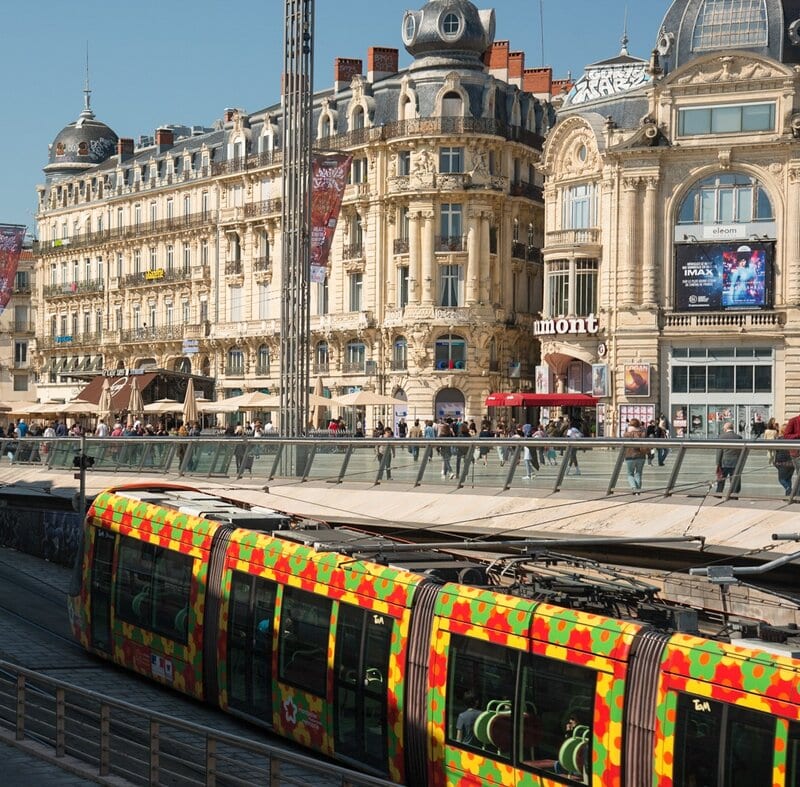 Der Place de la Comédie in Montpellier mit prächtigen Gebäuden und einer farbenfrohen Straßenbahn.