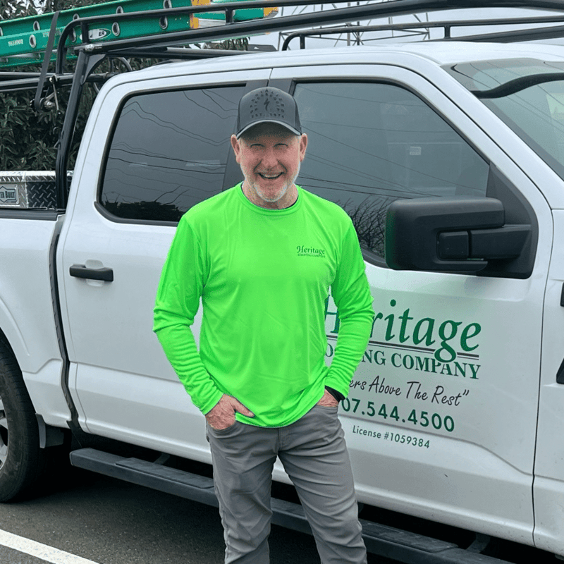 Employee at Heritage Roofing in front of the company truck
