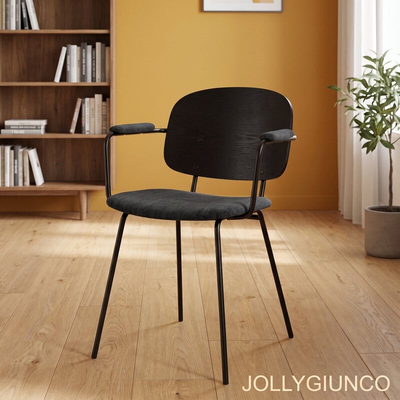 Empty black chair with metal legs in a warm home office setting; left is a wooden bookshelf and right is a potted plant against an orange wall.