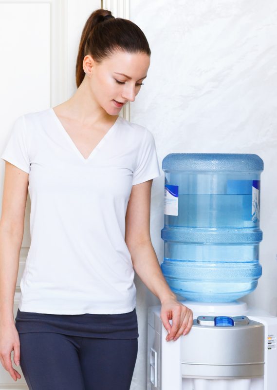 woman using water dispenser in gym clothes