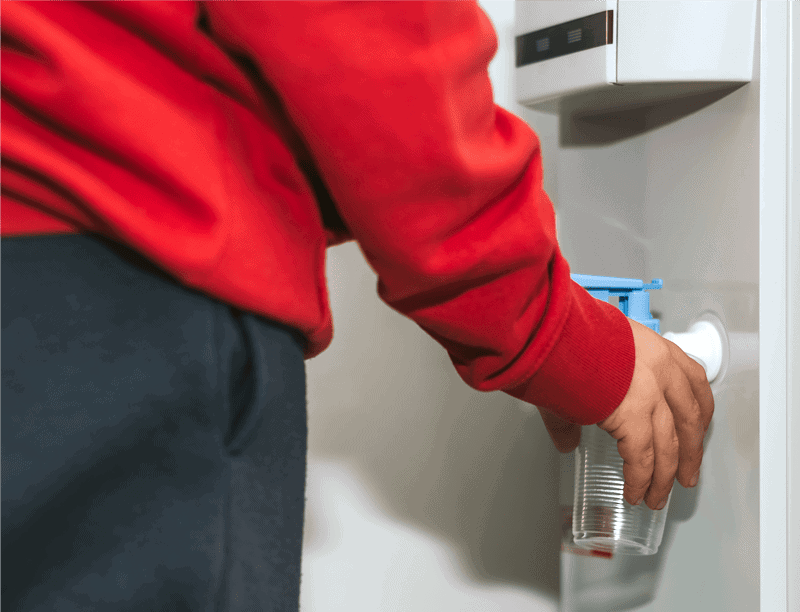 school boy filling up water bottle