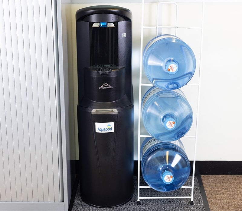 Contactless bottled water cooler with three water bottles in rack