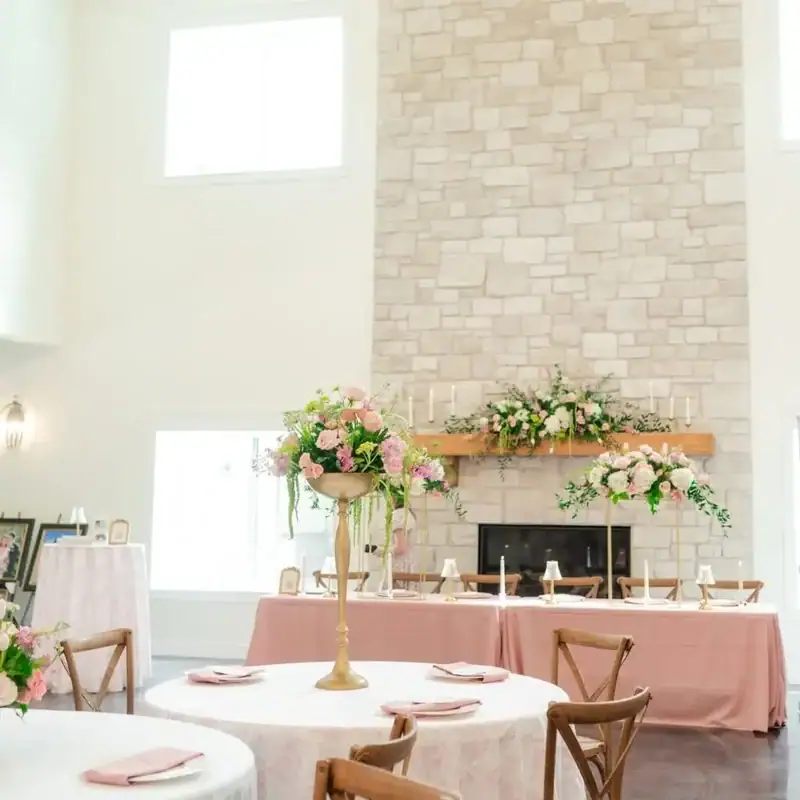 Stone fireplace mantel decorated with floral arrangements in the reception hall at Romaine Valley Weddings & Events in Fenton, Missouri