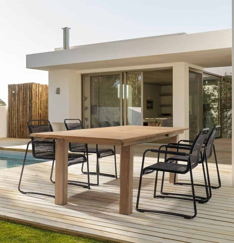 Tavolo in legno e sedie da esterno, arredo giardino moderno con vista sulla casa bianca.