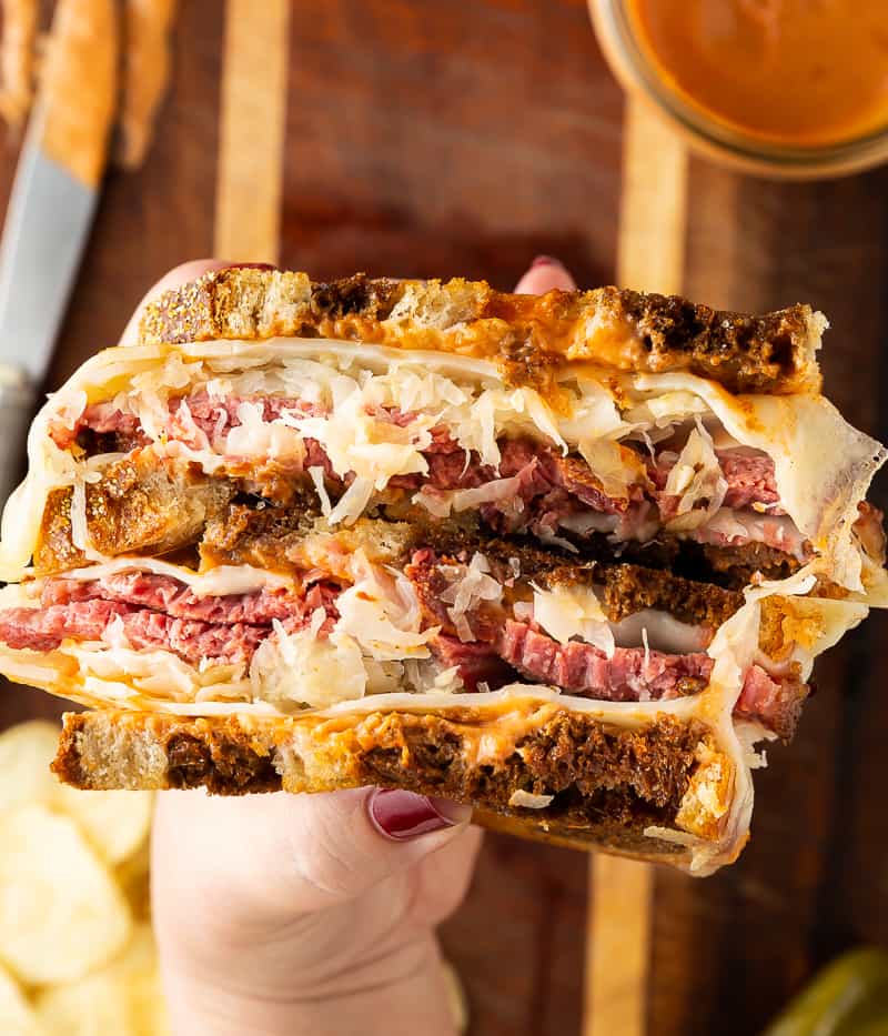 hand holding a reuben cut in half