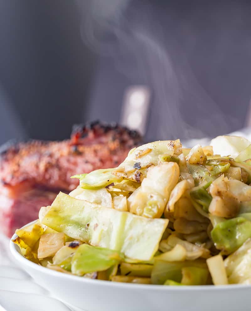 Steaming sauteed cabbage in a bowl with corned beef in the background