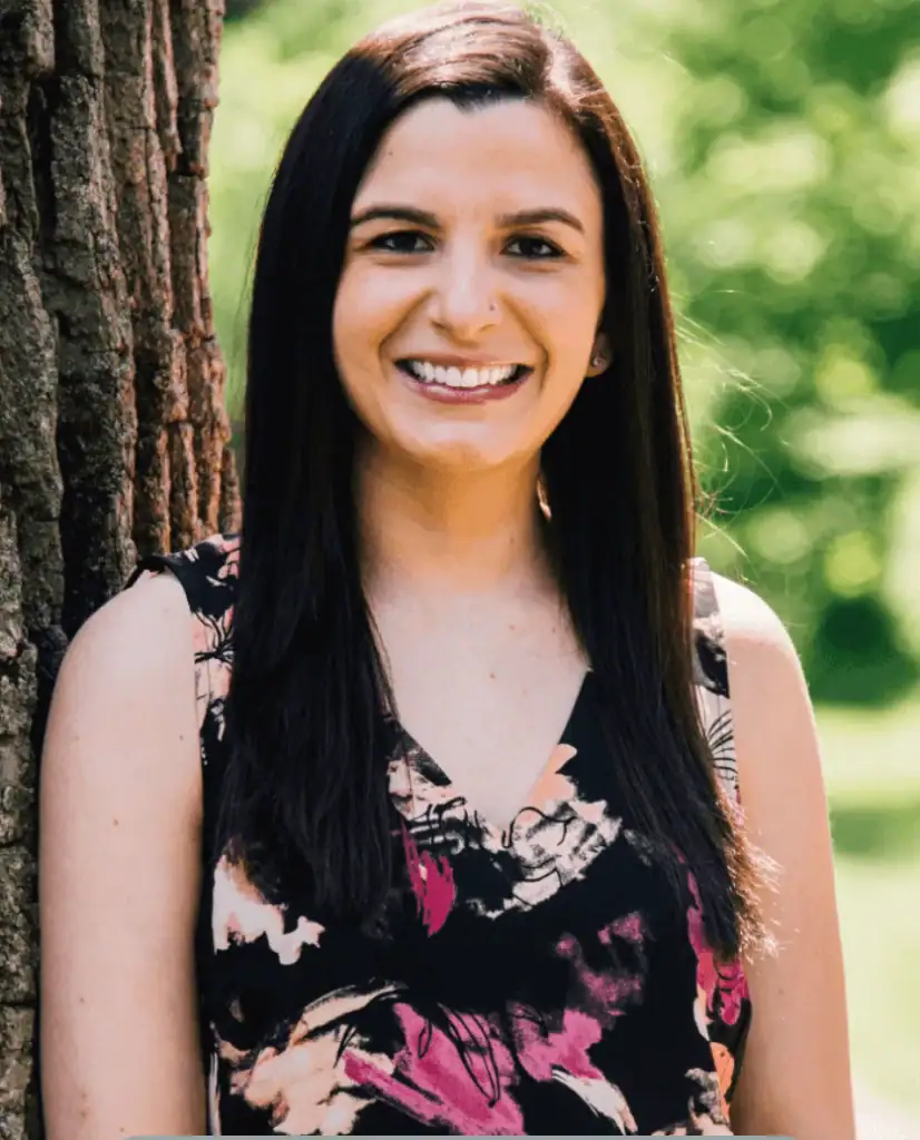 Sarah Rollins, LMSW SEP, founder and somatic experiencing therapist at Embodied Wellness, smiling outdoors in a sunlit park