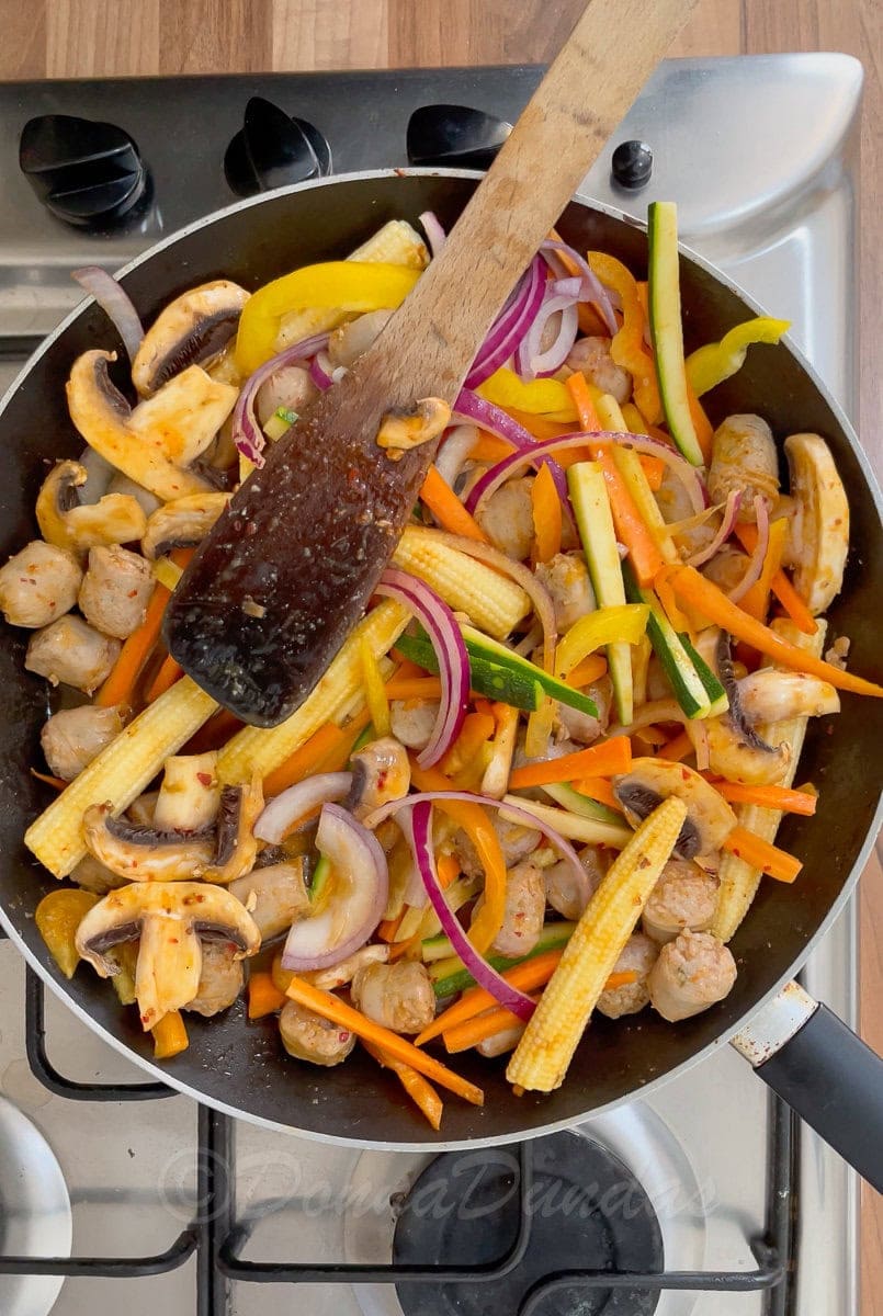 sausages and vegetables in frying pan.