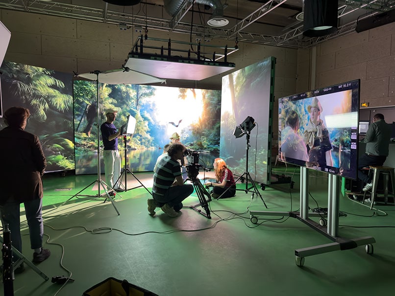 Tournage en cours sur le plateau virtuel d’Orly : trois panneaux LED affichent une jungle, un comédien joue devant, l’équipe travaille à la caméra et au retour vidéo sur pied