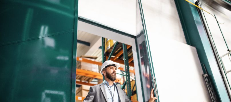 Employee in a hardhat opening a factory door