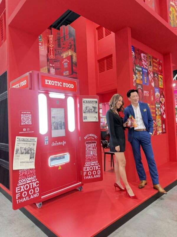 Couple posing next to a newspaper photo booth with a custom red brand wrap at a food trade fair