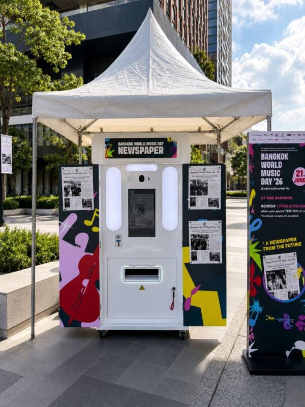 Newspaper photo booth with a colourful custom wrap under a white tent at an outdoor event