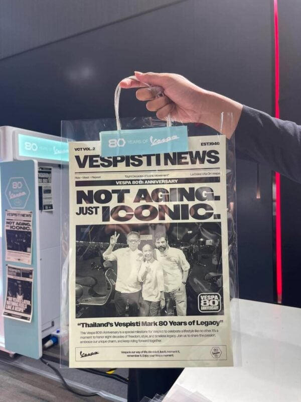 Hand holding a branded paper bag with a black and white newspaper photo print inside