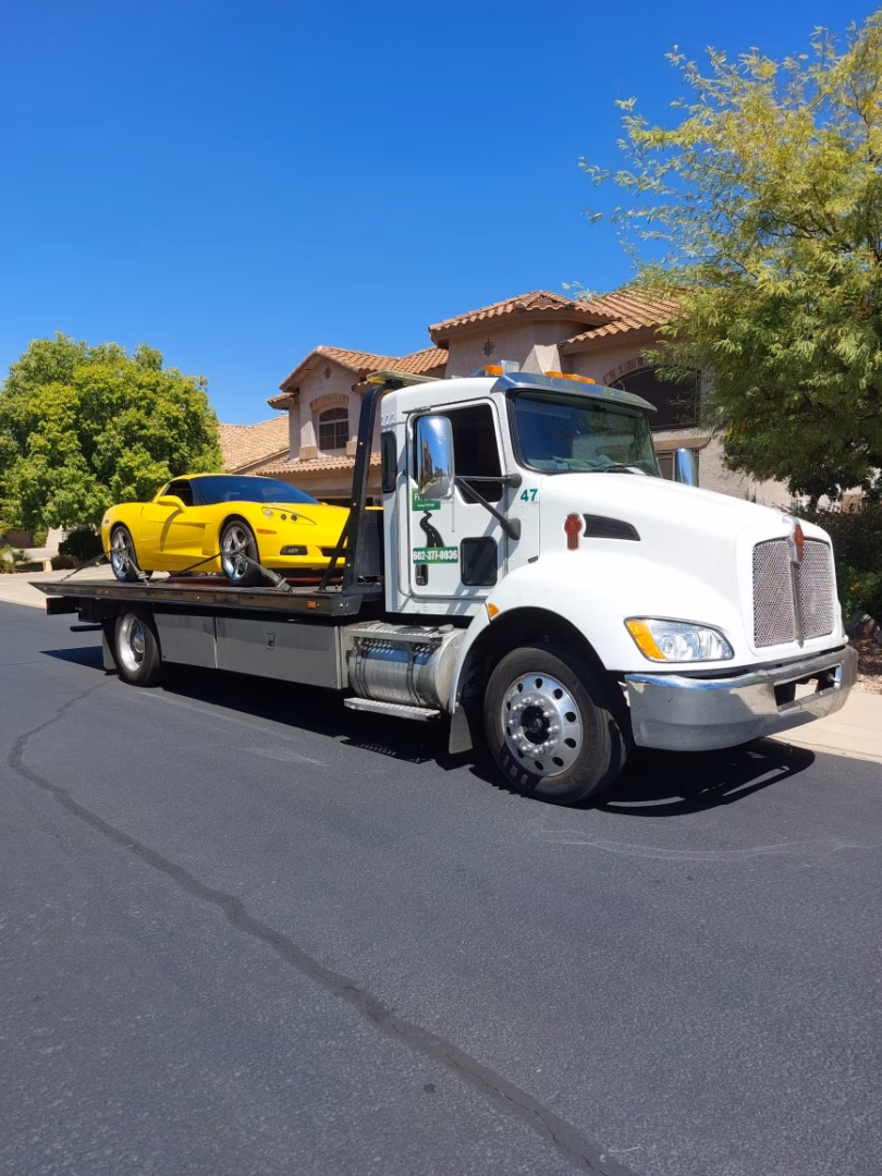 Freeway Towing & Storage flatbed tow truck hauling a yellow Corvette in Phoenix, AZ