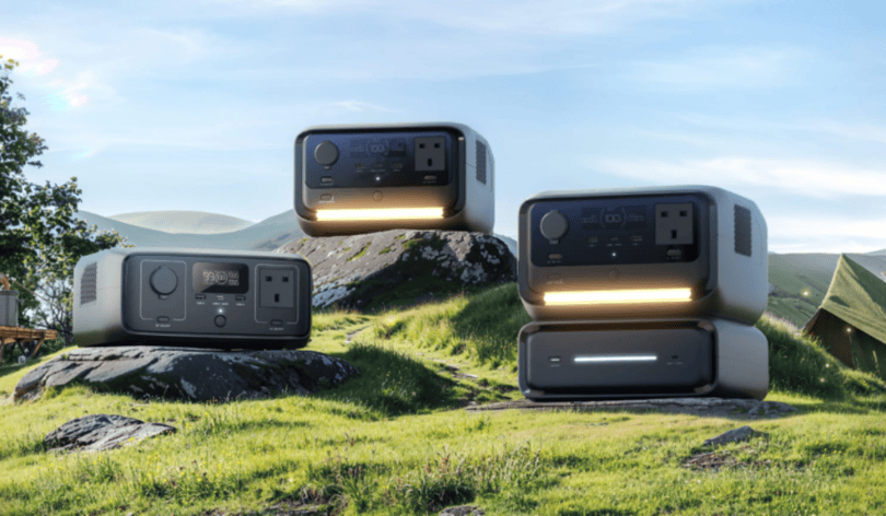 a picture showing a sunny landscape with green grass, blue skies and tents. Nestled on 3 rocks are 3 ecoflow river 3 battery prodructs.