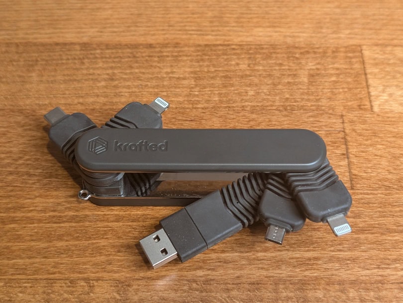 Multi-port USB charging hub with multiple connectors, including USB-C and USB-A, micro USB, and 2 lightning connections, on a wooden surface.