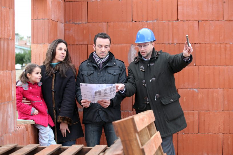 Eine Familie ist auf einer Baustelle, nachdem sie ein Grundstück über ein Erbbaurecht erlangt hat.
