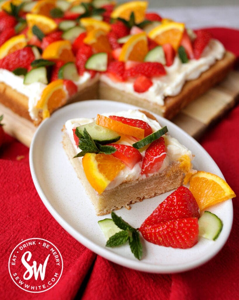 slice of the pimms traybake with cream cheese buttercream and lots of fresh strawberries.