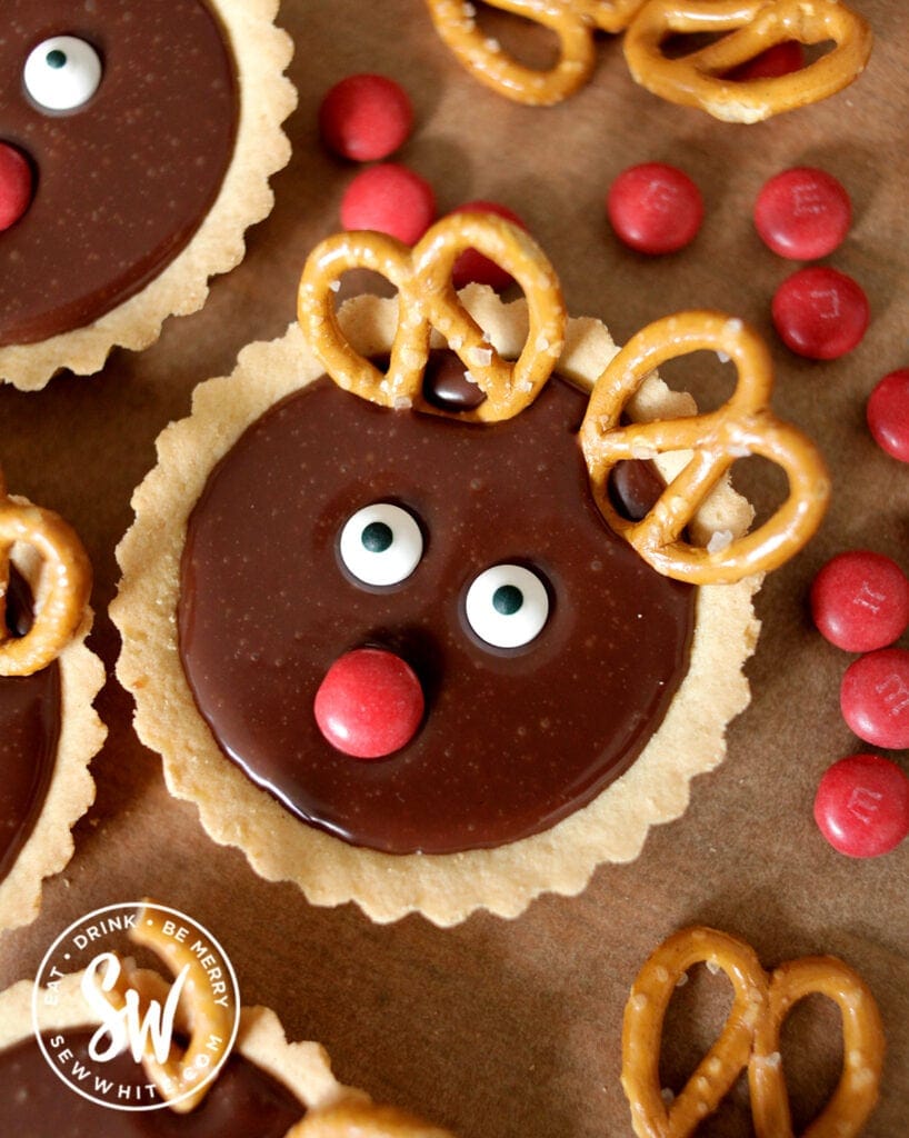 individual reindeer tarts on a greaseproof paper background. Chocolate tarts with pretzel antlers