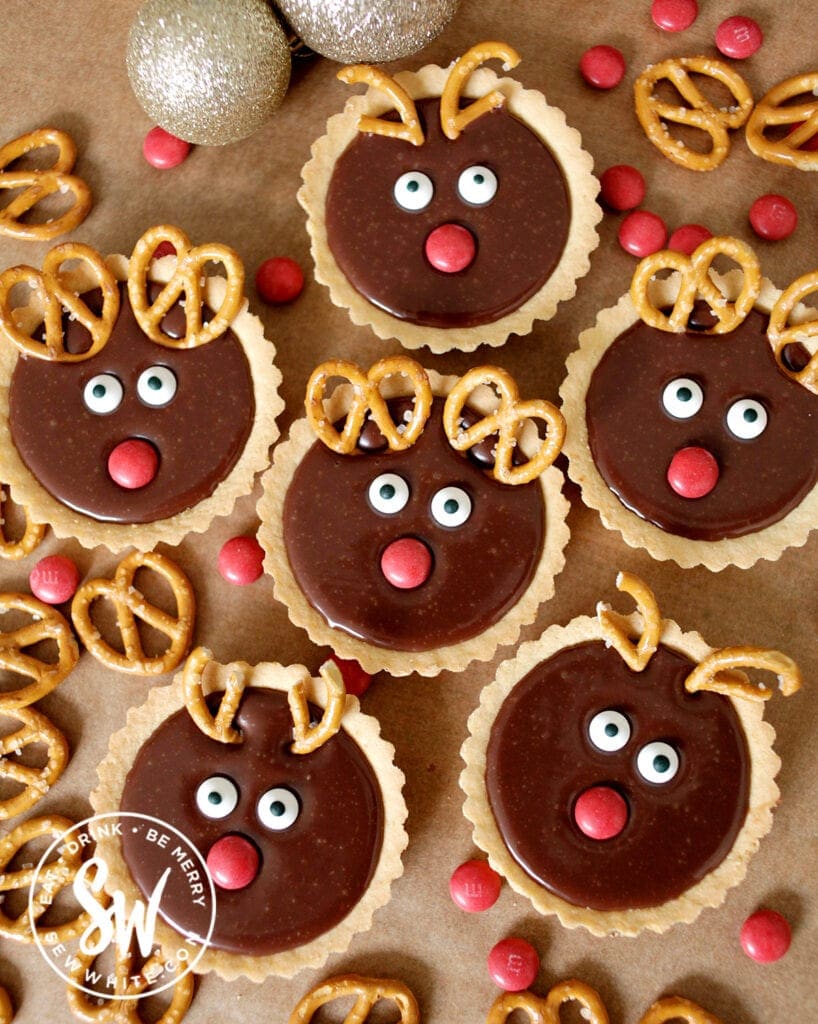 individual reindeer tarts on a greaseproof paper background. Chocolate tarts with pretzel antlers