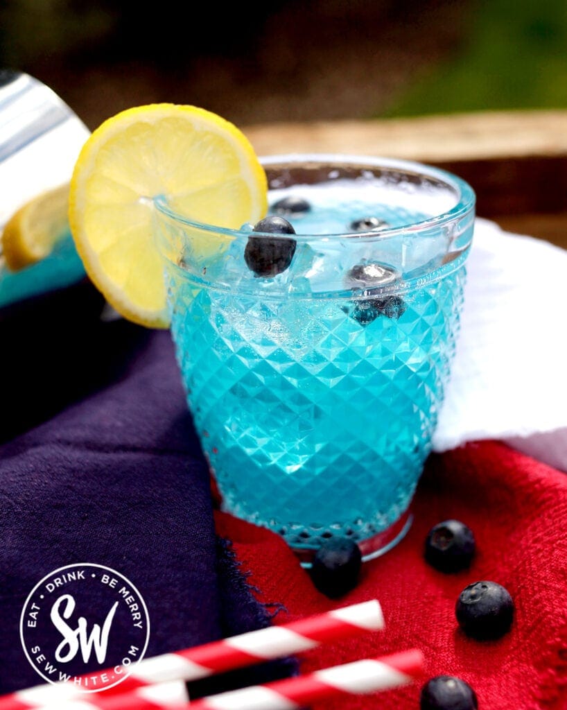 Blue Curacao Cocktail Recipe with a lemon wheel and fresh blueberries