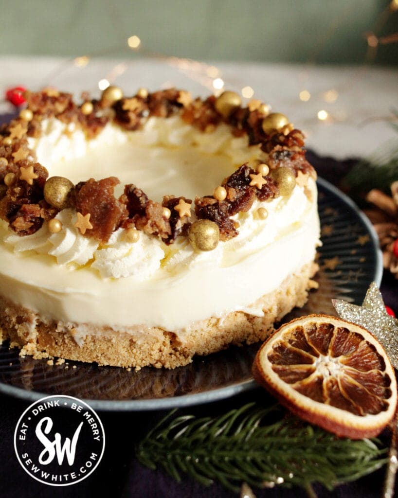 Christmas Pudding cheesecake on a blue plate with a dried orange slice.